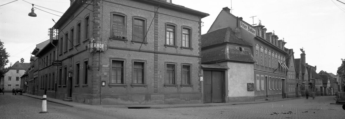 Das Foto zeigt den Hochheimer Gasthof "Kaiserhof" in einer ruhigen Straßenecke. Die Fassade besteht aus roten Ziegelsteinen, und ein altes Firmenschild ragt über den Gehweg.