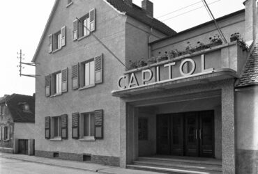 Das Foto zeigt das Gebäude des Hochheimer Kinos "Capitol". Über dem Eingang befindet sich der Schriftzug des Kinos. Das Gebäude ist an einer ruhigen Straße gelegen.