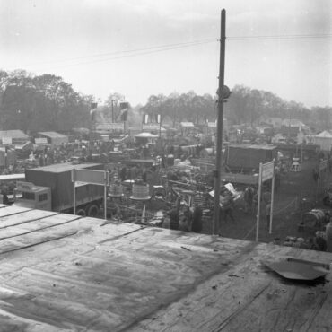 Das Bild zeigt eine Landmaschinenaufstellung auf dem Hochheimer Markt im Jahr 1949. Über das Gelände verteilt sind verschiedene landwirtschaftliche Geräte und Maschinen zu sehen, während Besucher in Gruppen herumlaufen und die Ausstellungsstücke begutachten.